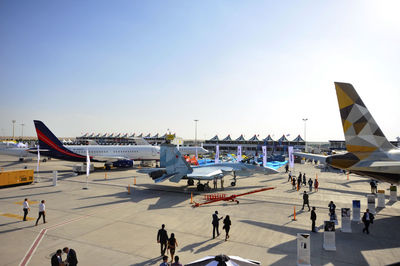 People on airport runway against clear sky