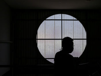 Rear view of woman looking through window