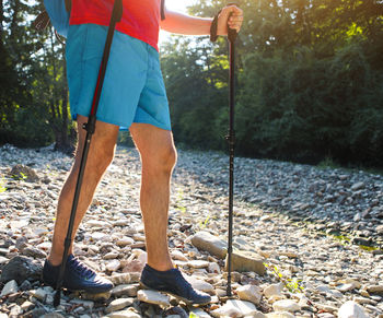 Low section of man standing on rock by river