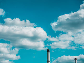 Low angle view of two chimneys against cloudy sky