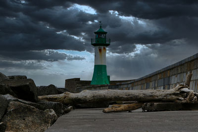 Lighthouse amidst buildings against sky