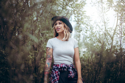 Young woman wearing hat while standing in forest