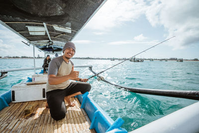 Portrait of young man sitting on boat in sea