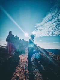 People standing on rock against sky