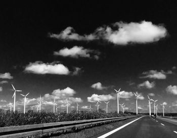 Wind turbines on road against sky