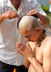 Man cutting hair of monk during ordination