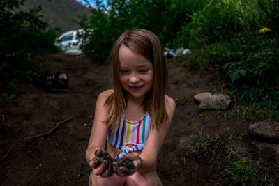 Center portrait of young girl with muddy hands on the bank of a river