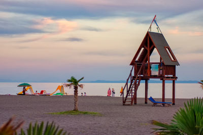 Lifeguard hut on beach against sky during sunset