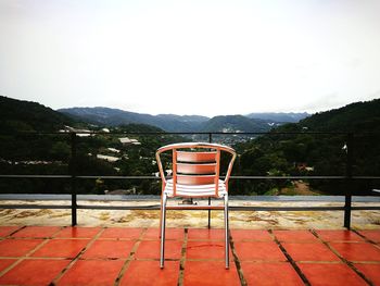 Deck chairs by railing against sky