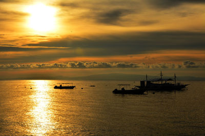 Silhouette boat in sea against sky during sunset