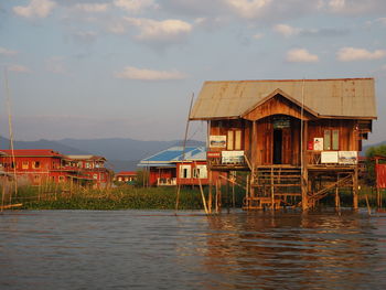 Houses by lake against sky