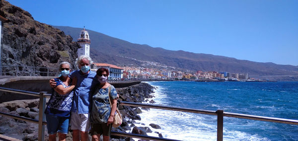 Senior people standing by railing against sea and sky