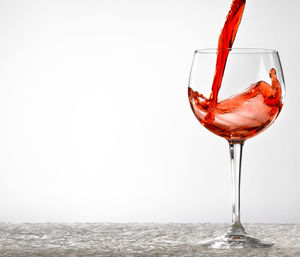 Close-up of wineglass on glass against white background