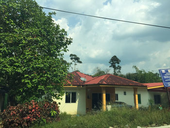 House and trees on field against sky