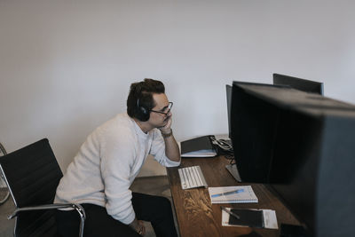 Businessman with hand on chin working over computer at desk in creative office