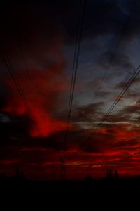 Low angle view of electricity pylon against cloudy sky