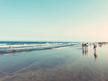 People walking at beach against sky