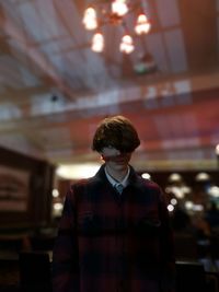 Teenage boy standing in illuminated restaurant