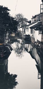 Canal by buildings in city against sky