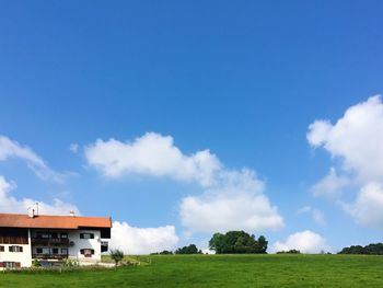 Houses on grassy field against cloudy sky