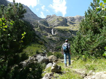 Rear view of hiker standing on mountain against sky