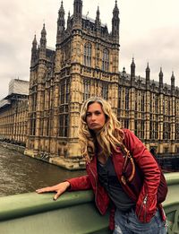 Portrait of young woman wearing leather jacket at westminster bridge in city