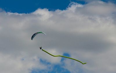 Low angle view of birds flying against cloudy sky