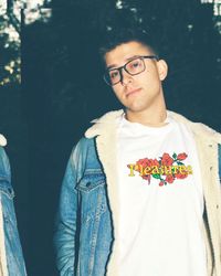 Portrait of young man standing against tree