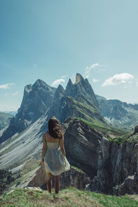 Rear view of woman standing on mountain against sky