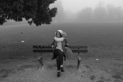 Full length of woman sitting on bench at park