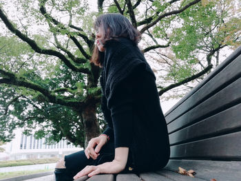 Side view of woman sitting in park