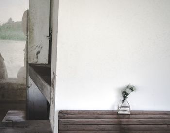 Close-up of flower vase on table against wall at home