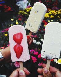 Cropped hands of people holding flavored ice outdoors