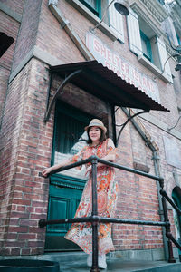 Portrait of woman standing against building