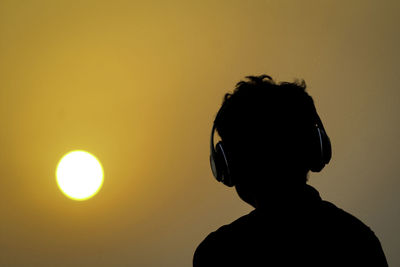 Rear view of silhouette man against orange sky