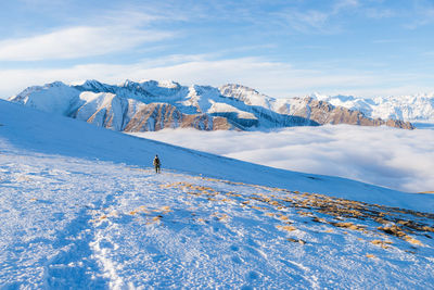 Distant view of woman hiking on snowcapped mountain