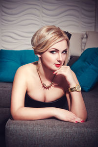 Portrait of beautiful young woman sitting on sofa