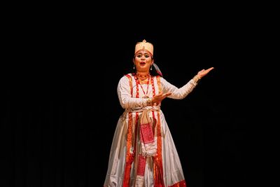 Portrait of woman standing against black background