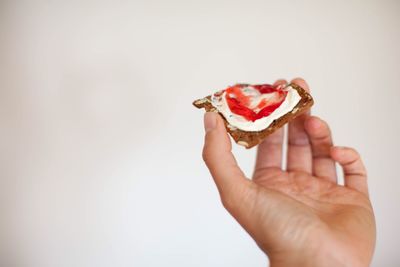 Close-up of hand holding ice cream over white background
