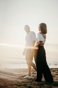 Rear view of couple at beach against sky