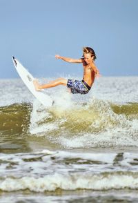 Shirtless boy surfing in sea