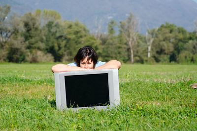 Woman with television set on field against sky