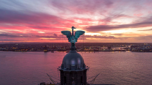 Statue against sea during sunset