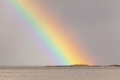 Scenic view of rainbow over sea against sky