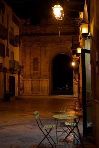 Empty chairs and tables in illuminated building at night