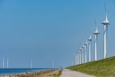 Traditional windmill on field against clear blue sky, 