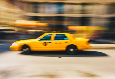 Blurred motion of yellow car on road
