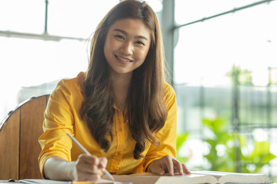 Smiling businesswoman reading book while sitting in office