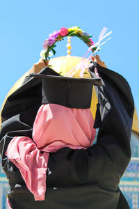 Low angle view of person holding umbrella against blue sky