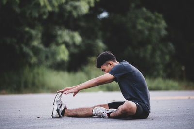 Full length of young man sitting on road